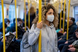 Beautiful young woman riding on the metro wearing a facemask to avoid an infectious disease - COVID-...