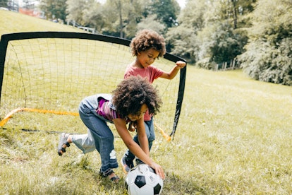 Shot of elementary aged kids playing soccer together in the school field during recess.