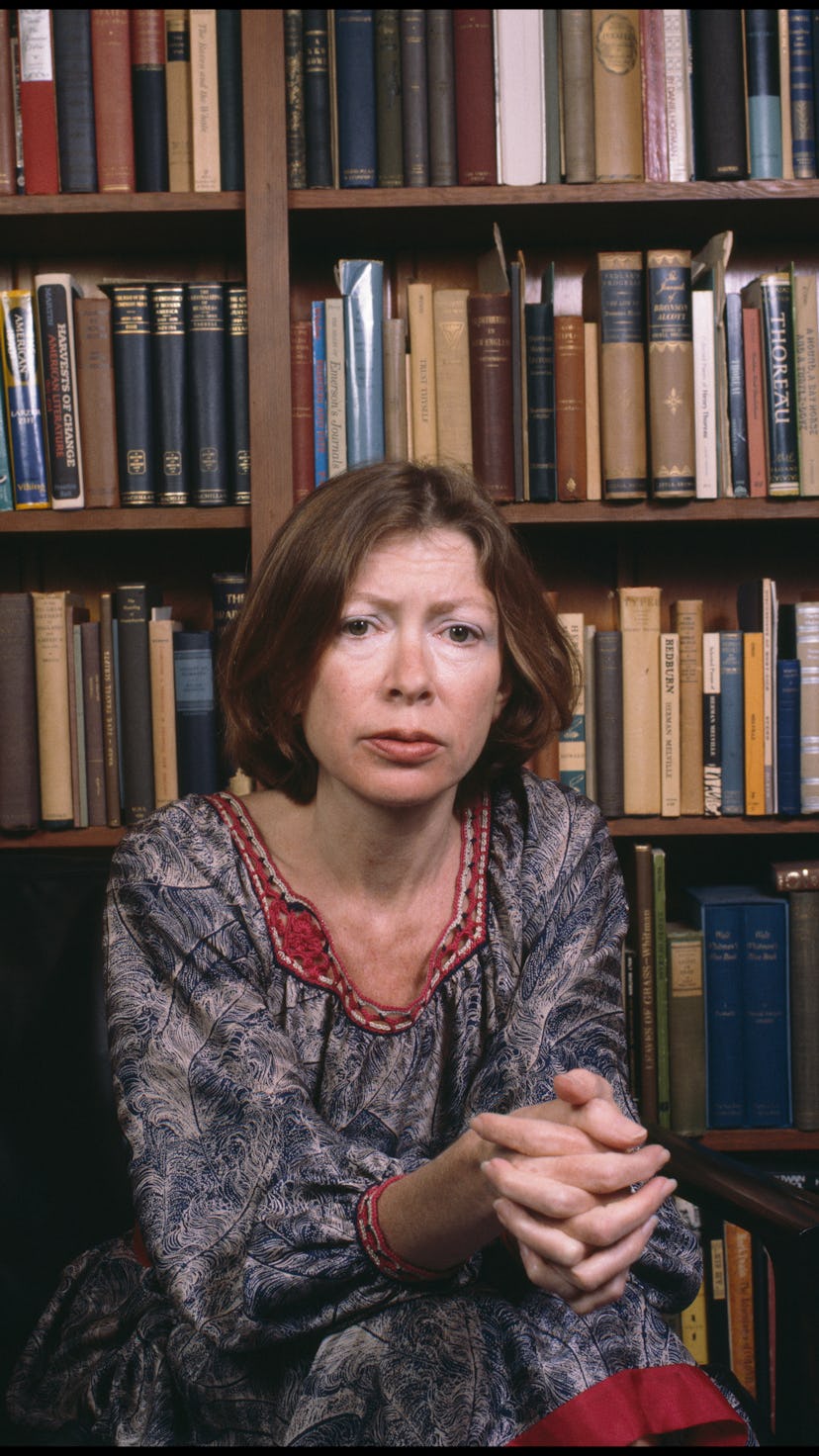 Portrait of American author Joan Didion as she sits in a chair in front of a bookshelf, Berkeley, Ca...