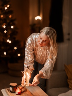 A woman lights candles during the holidays. Here's your daily horoscope for Christmas weekend: Decem...
