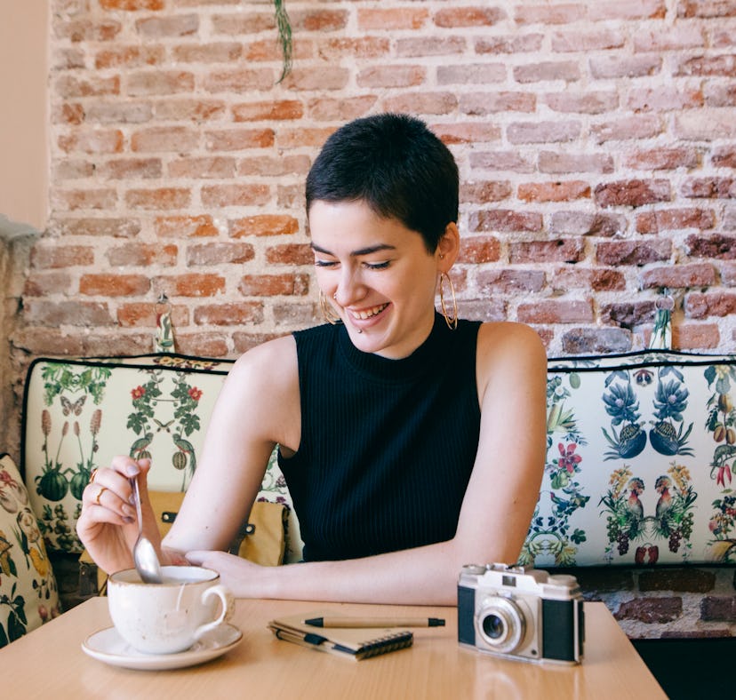 A happy woman drinking tea could use some gratitude affirmations to use with Instagram pictures.