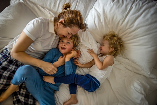 Photo of mother and her boys playing together in bed