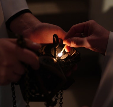 KALININGRAD, RUSSIA - DECEMBER 24, 2020: Roman Catholic believers light charcoal in an incense burne...