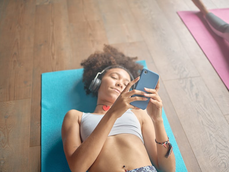 A woman looks at her phone for free fitness app deals for January 2022 at-home workouts. 