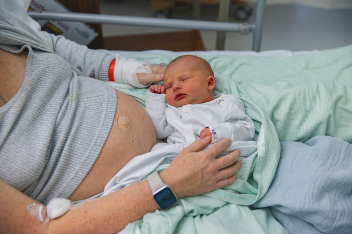 postpartum mom in hospital bed with infant in lap