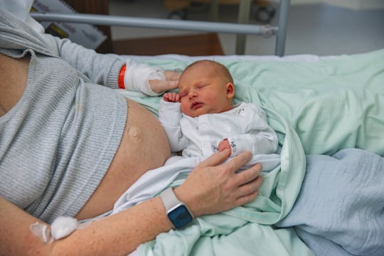 postpartum mom in hospital bed with infant in lap