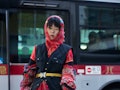 A guest is seen wearing black utility vest, red plaid skirt, red knit hood, red top and red knit arm...