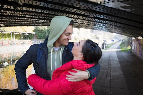 Happy, affectionate young couple hugging under urban bridge along canal