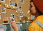 Woman at home pinning up vision board quotes as part of her vision board 2022.