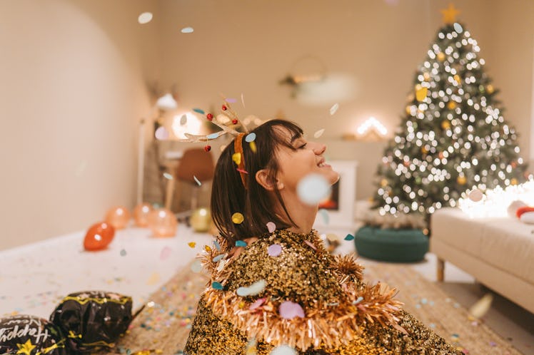 Photo of a smiling woman sitting on the floor after the New Year's Eve party and posting New Year's ...