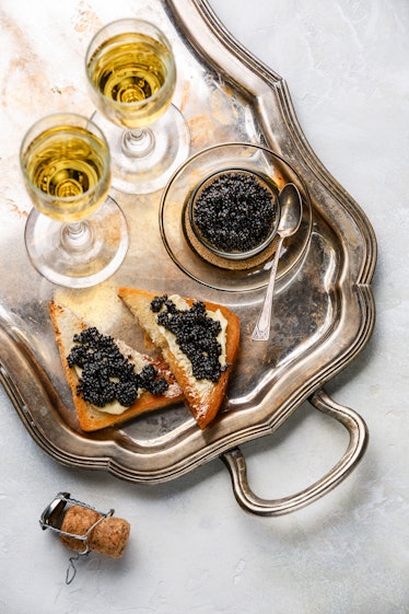 Sturgeon black caviar, sandwiches and champagne on silver tray