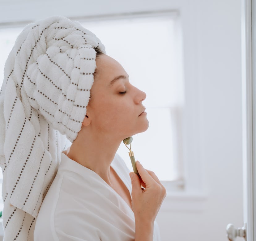 Woman using jade roller on her face at home