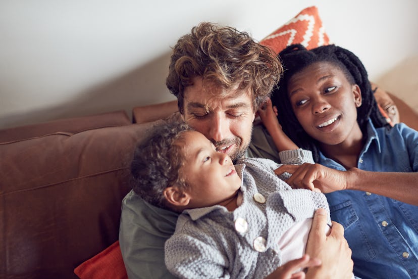 Happy, affectionate young multiracial family cuddling on sofa