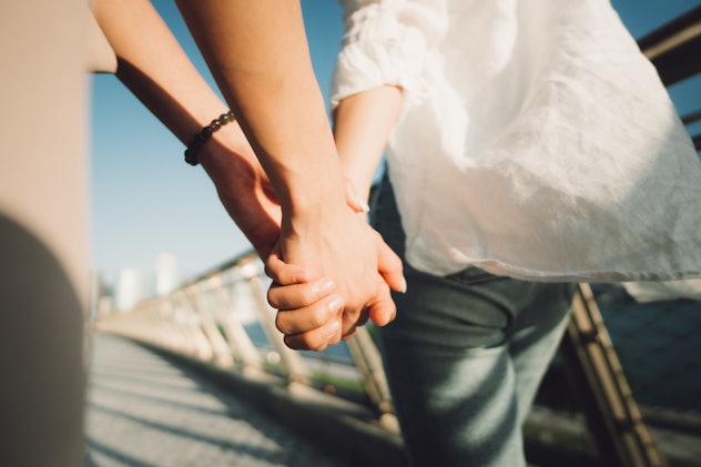 Close up shot of a lesbian couple holding hands and walking along the promenade.