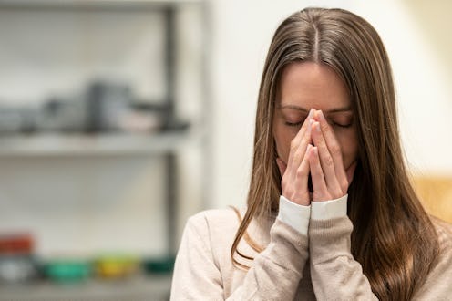 Front shot of tired adult woman covering face with hands