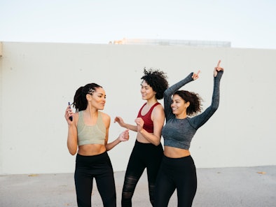 three women smiling and dancing together as they think about the zodiac signs most likely to sing ou...
