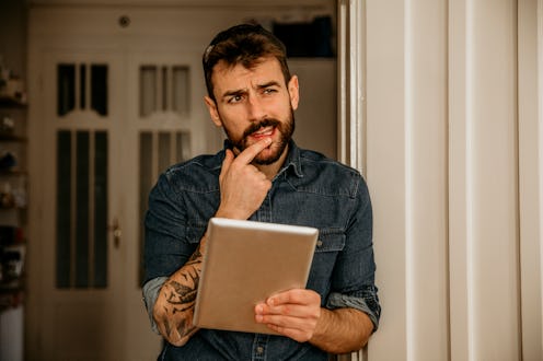 Cropped shot of a young student/businessman in a denim shirt working on his tablet in the office. Co...
