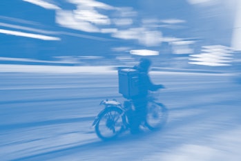 NEW YORK, USA - FEBRUARY 18: A food delivery guy with bicycle is seen as snowfall blankets the Times...