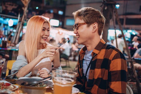 Smiling friends enjoying dinner on night market in Thailand.