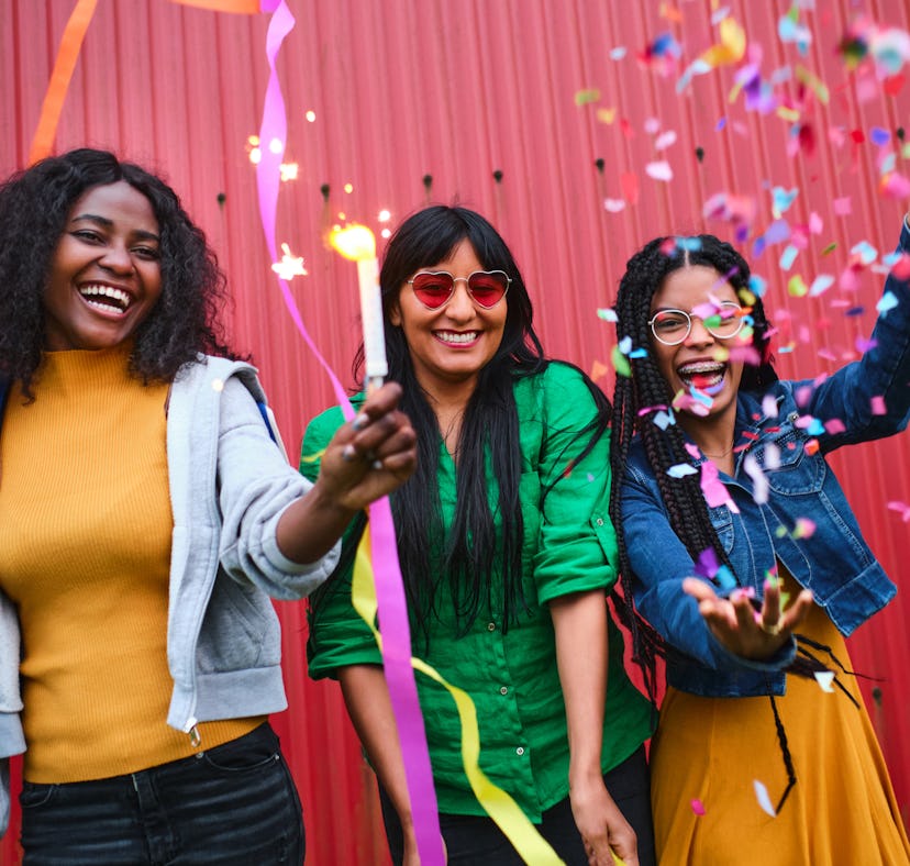 Three young women celebrating New Year's Eve with confetti and sparklers after reading the December ...