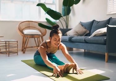 Shot of a young woman practicing yoga at home for the winter solstice.