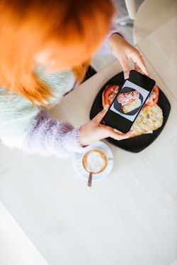 A woman takes a photo of her food. Food TikTokers make their predictions for 2022 food trends on Tik...