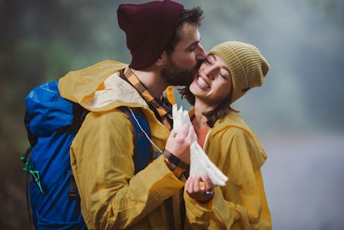 Affectionate man kissing his girlfriend during bad weather conditions in nature.