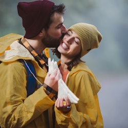 Affectionate man kissing his girlfriend during bad weather conditions in nature.