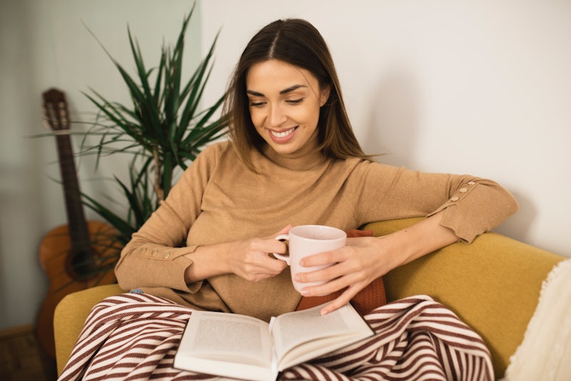 Woman enjoying at home, drinking coffee and reading a book.
