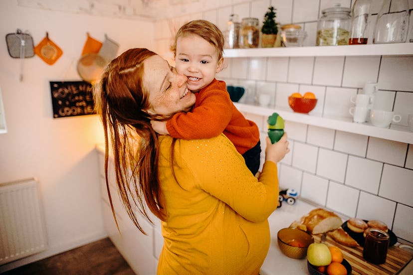 Pregnant mother and son exchange tenderness in the kitchen