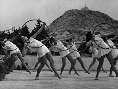 A group of Greek girls re-create the slow, rhythmic style of Ancient Greece. The hoops are used as s...