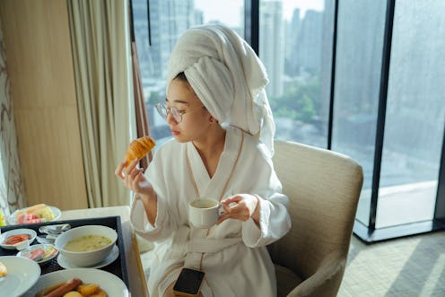 A woman eats a croissant in a hotel room. Here's your daily horoscope for December 6 2021.