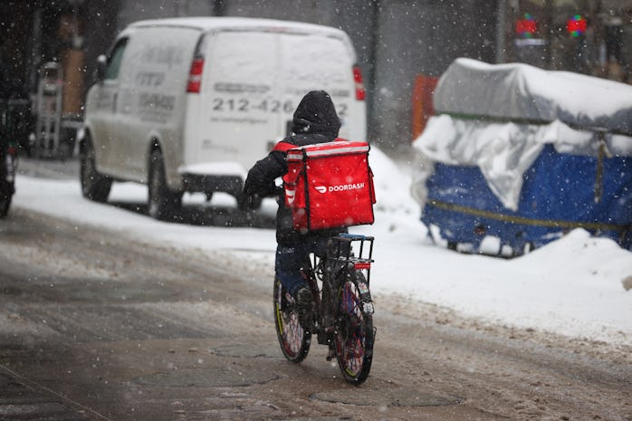 NEW YORK, USA - FEBRUARY 18: A food delivery guy with bicycle is seen as snowfall blankets the Times...