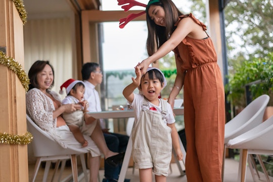 A multi generational family of Asian descent celebrates Christmas together at home. The image is foc...