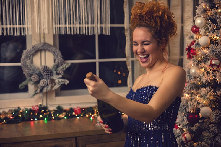 Youngwoman opening bottle of champagne at new year's party, for which she'll need Instagram captions...