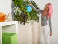 A woman waters her living wall, which is a 2022 home decor trend for Gen Z.