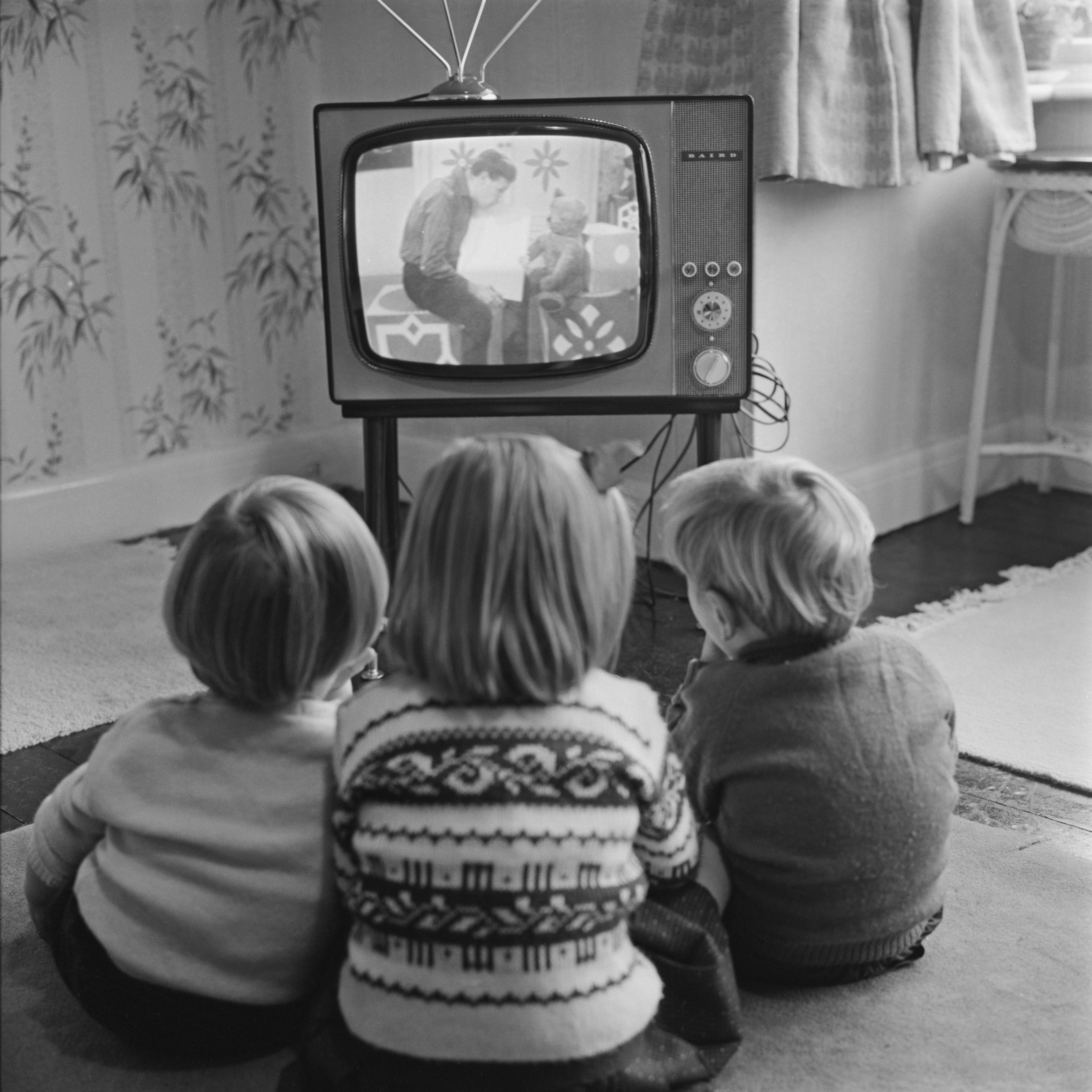 Four-year-old Claire Potter and her two-year-old twin brothers John and Hugh watch a children's tele...