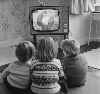 Four-year-old Claire Potter and her two-year-old twin brothers John and Hugh watch a children's tele...