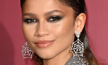 A closeup of Zendaya at a photocall for "Spiderman: No Way Home"  with spiderweb earrings 