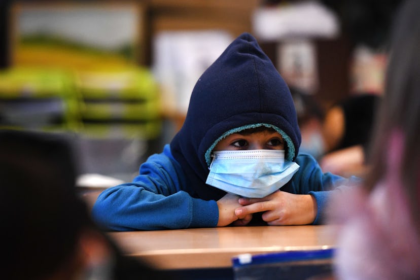 A boy wears a hat and a face mask as he attends lessons in his aerated classroom at the Petri primar...
