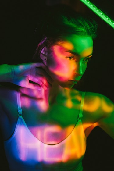 young woman lit by multi-colored lights reflects on sagittarius season 2021 ending