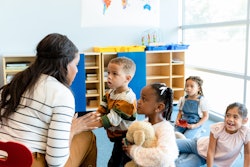 The mid adult female teacher patiently gives the preschool age children one-on-one instructions.