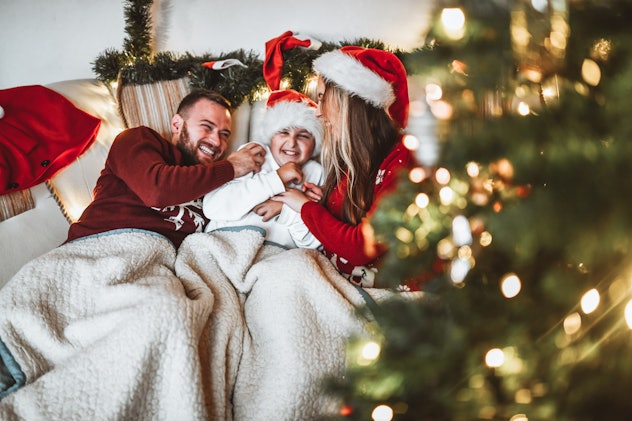 Family Warming Up Under Blanket For Christmas Eve And Sharing Happy Moments