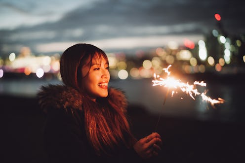 A woman lights a sparkler. Here's the luckiest day in 2022 for every zodiac sign.