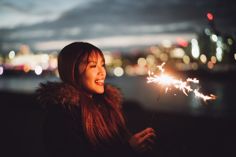 A woman lights a sparkler. Here's the luckiest day in 2022 for every zodiac sign.