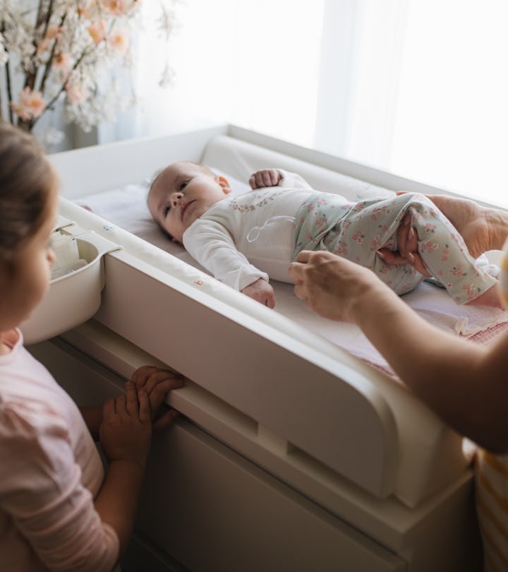 Little girl watching her mom change clothes of her little baby sister