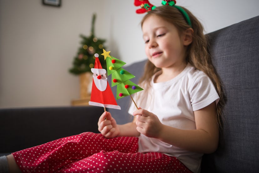 little girl holding santa and christmas tree puppets
