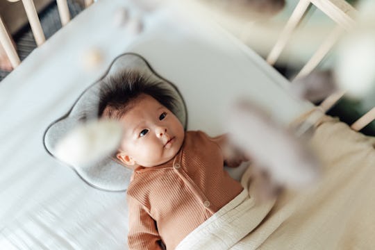 Asian newborn baby girl watching the cot mobile.