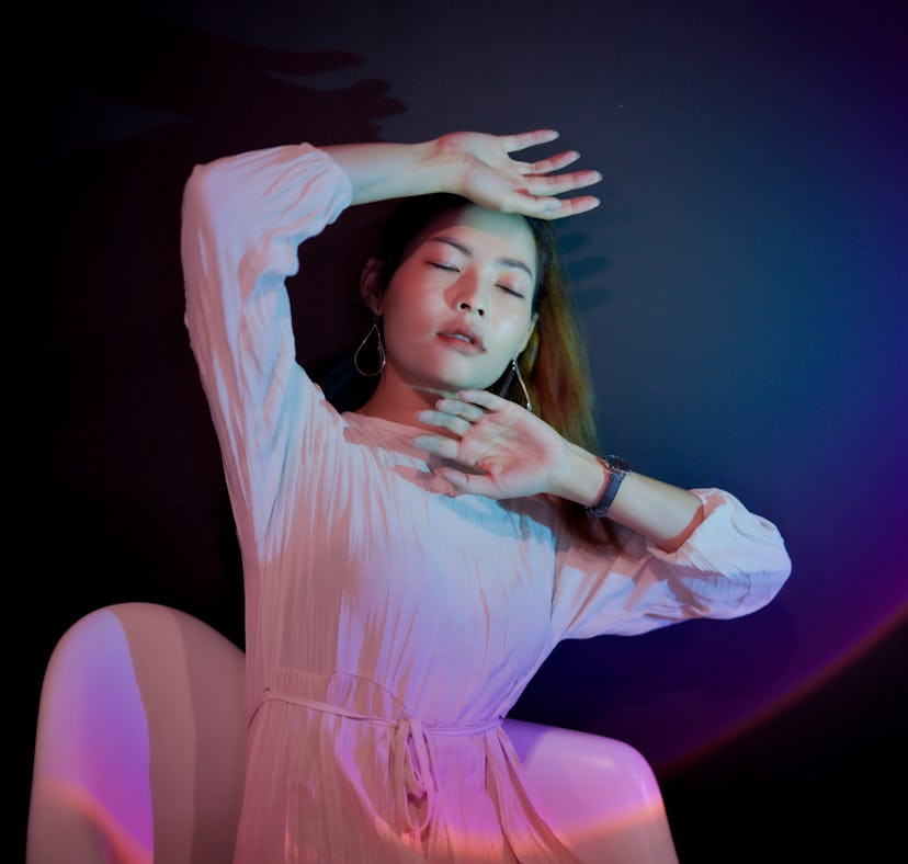 Young woman basking in pink light, thinking about how the January 2022 new moon in Capricorn will af...