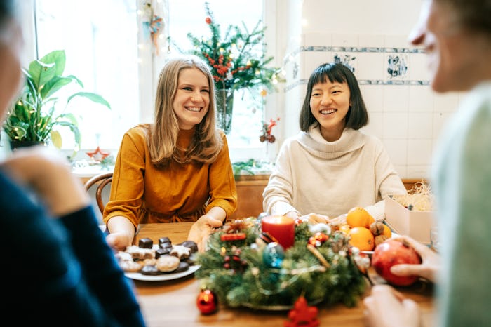 Group of women having food while sitting at festive table during Christmas. Multi-ethnic group of fe...